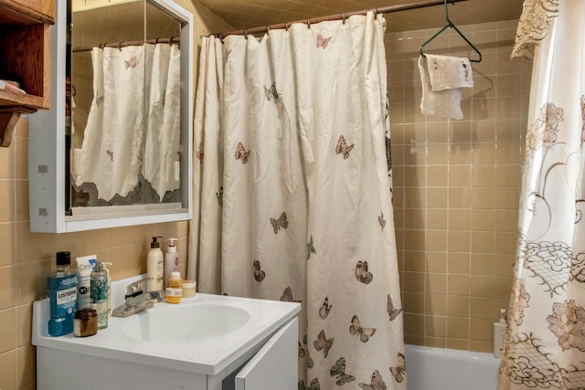 bathroom with shower / bath combo with shower curtain, tile walls, vanity, and tasteful backsplash