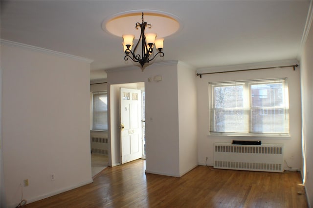 spare room with a notable chandelier, radiator heating unit, and crown molding