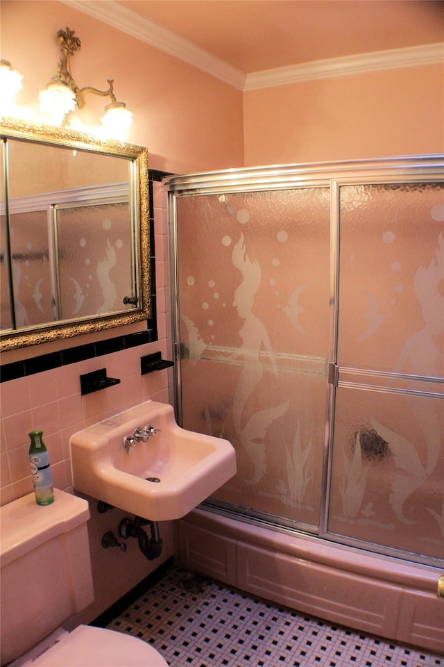 full bathroom featuring tile patterned floors, ornamental molding, sink, tile walls, and enclosed tub / shower combo