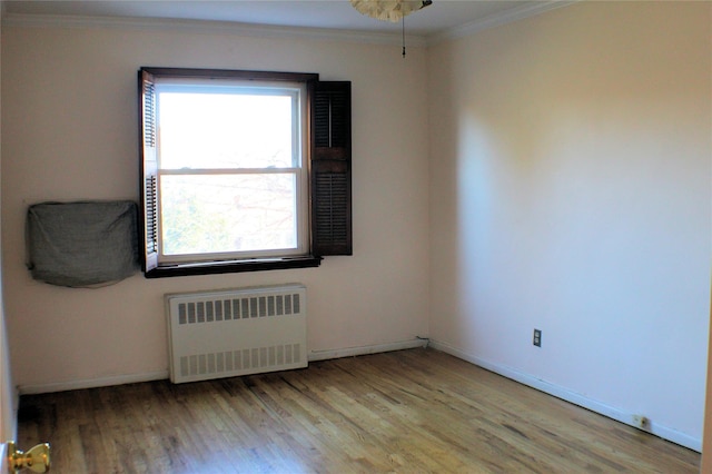 empty room with light hardwood / wood-style floors, ornamental molding, and radiator