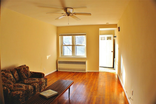 unfurnished living room with ceiling fan, radiator heating unit, and wood-type flooring