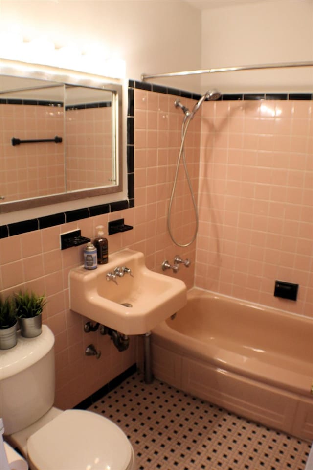 full bathroom featuring sink, tile patterned flooring, toilet, tile walls, and tiled shower / bath