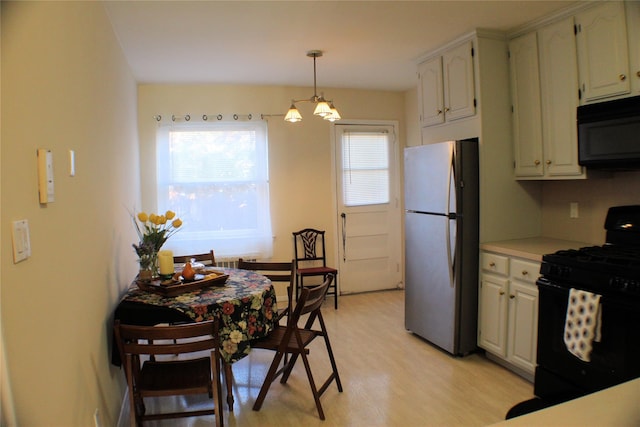 kitchen featuring light hardwood / wood-style flooring, a chandelier, pendant lighting, white cabinets, and black appliances