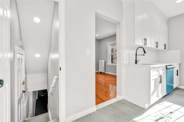 kitchen featuring sink, dishwasher, white cabinets, radiator heating unit, and light tile patterned flooring