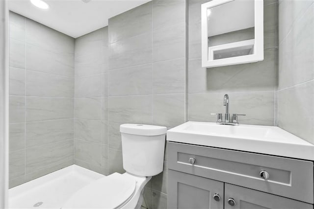 bathroom featuring vanity, toilet, tile walls, and walk in shower