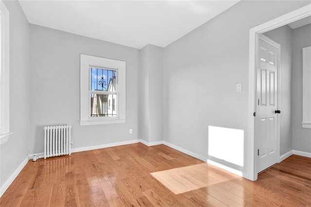 spare room featuring radiator and light hardwood / wood-style flooring