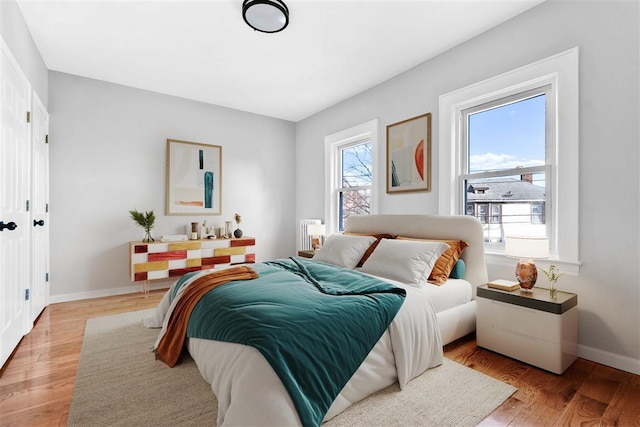 bedroom with light hardwood / wood-style floors and multiple windows