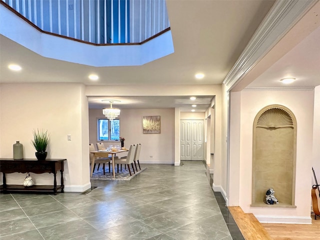 hallway with a notable chandelier, a towering ceiling, and ornamental molding