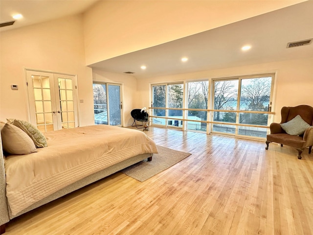 bedroom featuring access to exterior, light hardwood / wood-style flooring, high vaulted ceiling, and french doors