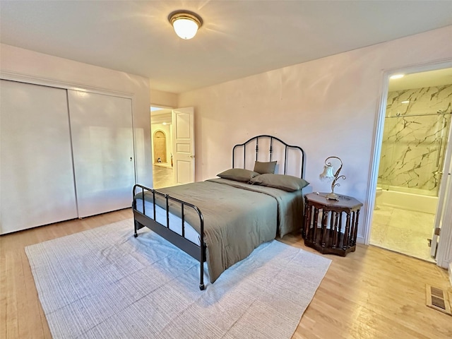 bedroom featuring connected bathroom, light hardwood / wood-style flooring, and a closet