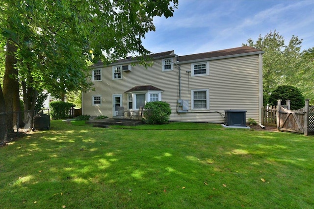 rear view of house with cooling unit and a yard