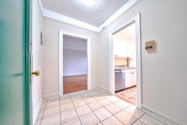 hall featuring sink, crown molding, and light tile patterned flooring