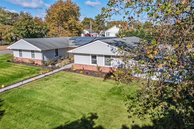 view of front of home with a front lawn and solar panels