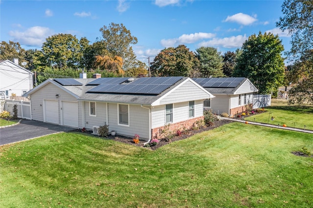 ranch-style house featuring a garage, a front yard, and solar panels