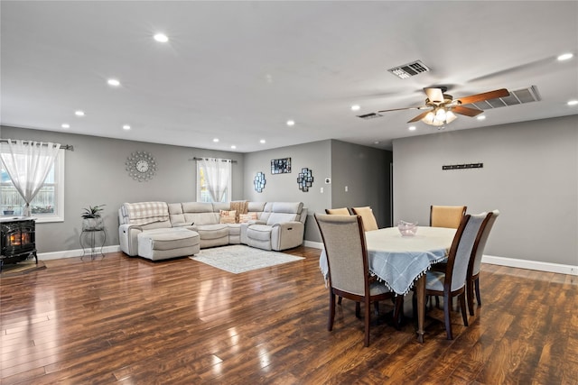 dining space featuring dark wood-type flooring, ceiling fan, plenty of natural light, and a wood stove