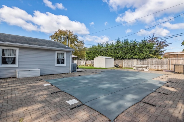 view of swimming pool featuring central air condition unit, a shed, and a patio