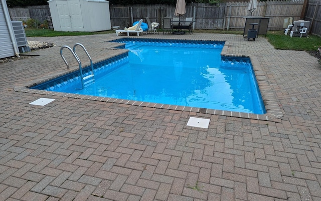 view of pool with central AC, a storage unit, and a patio area