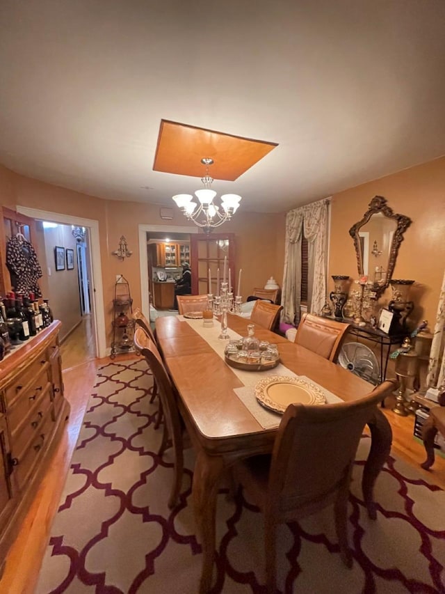 dining area with light wood-type flooring and an inviting chandelier