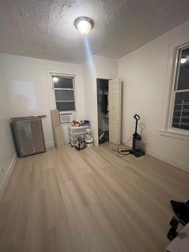 interior space featuring hardwood / wood-style flooring, cooling unit, and a textured ceiling