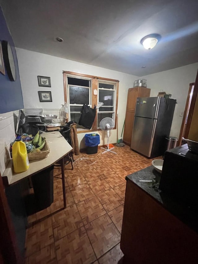 kitchen with a kitchen bar, stainless steel fridge, and dark parquet floors