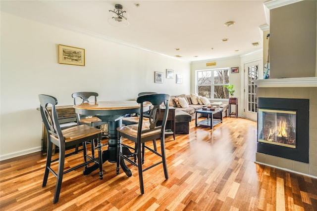 dining area with light wood-type flooring and ornamental molding