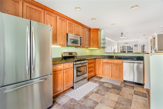 kitchen with dark stone counters, appliances with stainless steel finishes, and sink