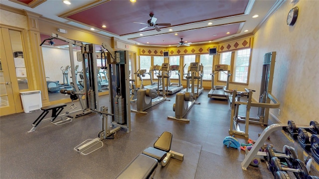 workout area featuring ceiling fan, a tray ceiling, and ornamental molding