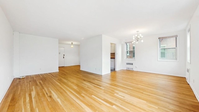 unfurnished living room featuring radiator heating unit, a chandelier, and light wood-type flooring