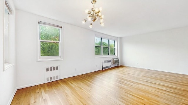 spare room featuring radiator heating unit, healthy amount of natural light, a chandelier, and light wood-style flooring