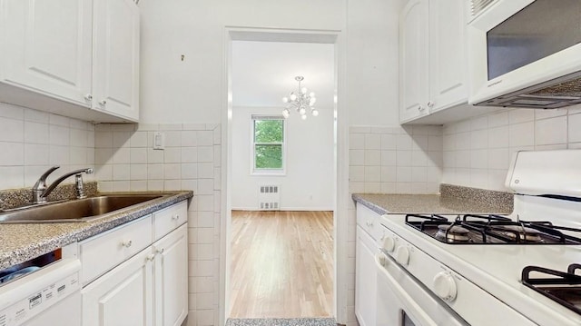 kitchen featuring white appliances, a sink, white cabinetry, radiator, and light wood finished floors