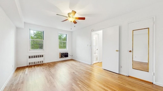spare room with radiator, light wood-style flooring, ceiling fan, and baseboards