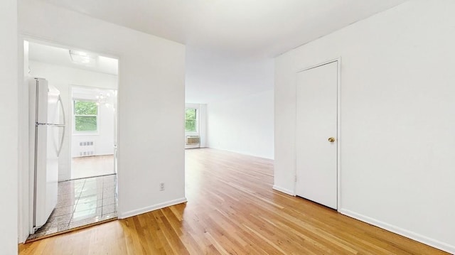 unfurnished room with radiator heating unit, light wood finished floors, and baseboards