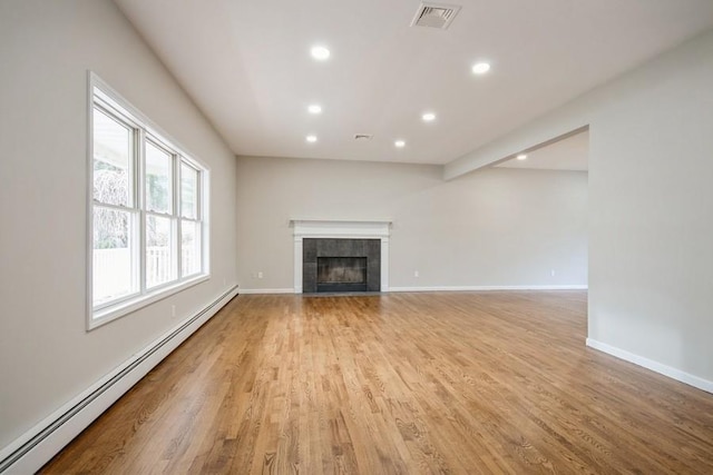 unfurnished living room with baseboard heating, a fireplace, and light wood-type flooring