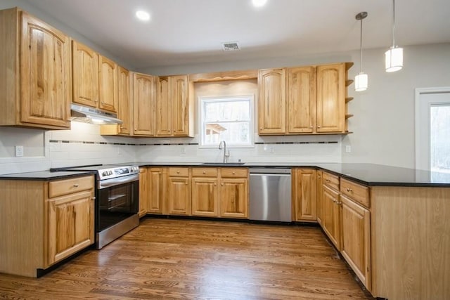 kitchen featuring appliances with stainless steel finishes, tasteful backsplash, sink, decorative light fixtures, and dark hardwood / wood-style floors