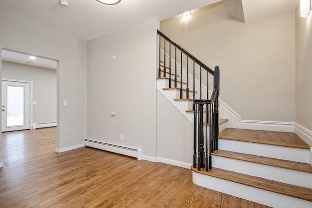 staircase featuring hardwood / wood-style flooring and a baseboard heating unit