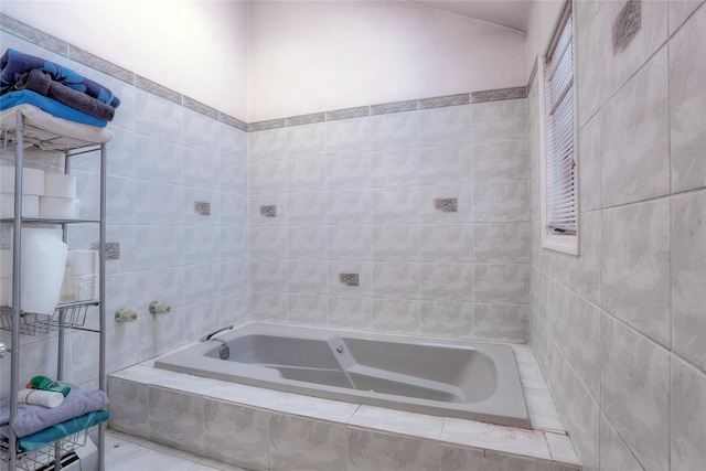 bathroom with a relaxing tiled tub and tile walls