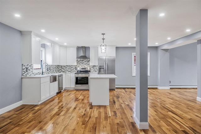 kitchen with wall chimney exhaust hood, stainless steel appliances, sink, decorative light fixtures, and white cabinetry