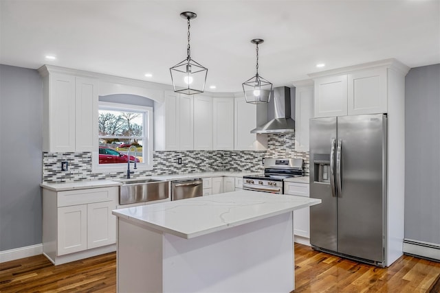 kitchen with white cabinetry, stainless steel appliances, wall chimney range hood, pendant lighting, and a kitchen island