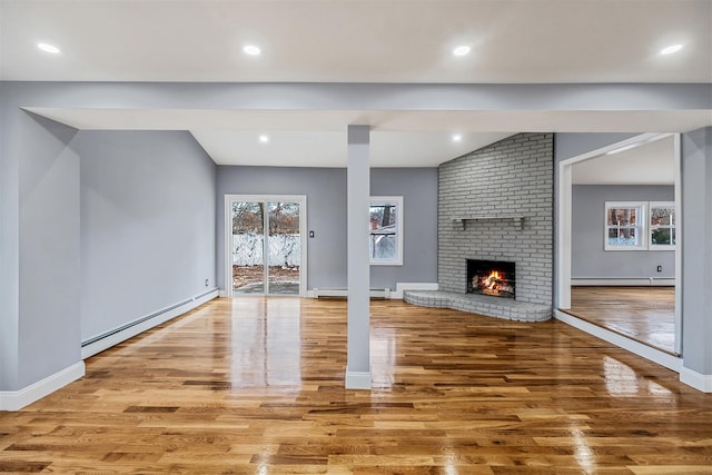 unfurnished living room featuring a brick fireplace, light hardwood / wood-style floors, and a baseboard heating unit