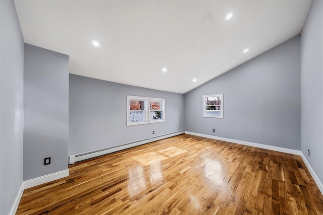 unfurnished room featuring hardwood / wood-style floors, a baseboard radiator, and lofted ceiling