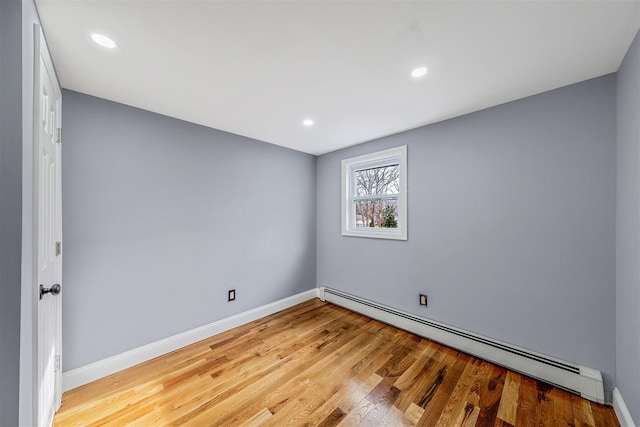 empty room with light wood-type flooring and a baseboard heating unit