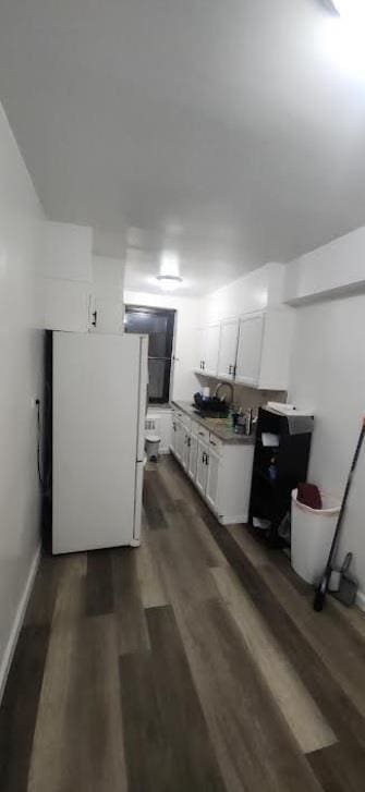 basement with white fridge and dark wood-type flooring