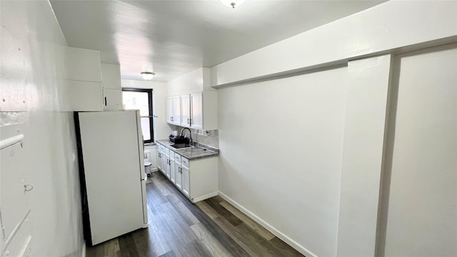 kitchen with stone countertops, sink, white cabinets, dark hardwood / wood-style flooring, and white fridge