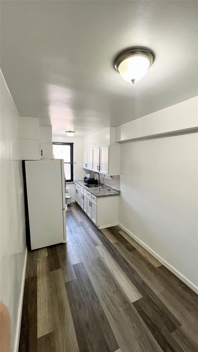 kitchen with dark wood-type flooring, sink, white fridge, light stone countertops, and white cabinets