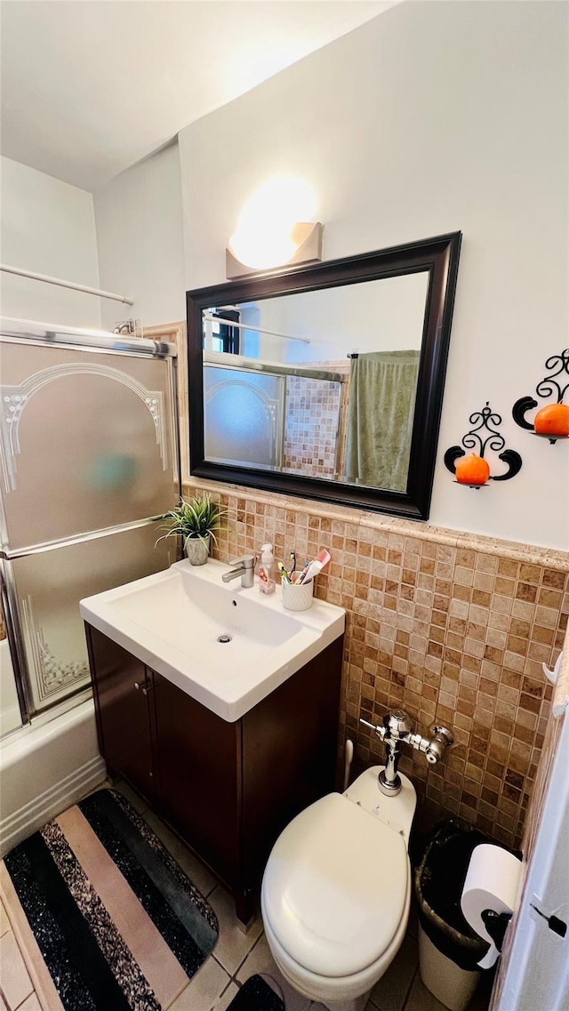 full bathroom with toilet, combined bath / shower with glass door, tile walls, vanity, and tile patterned flooring