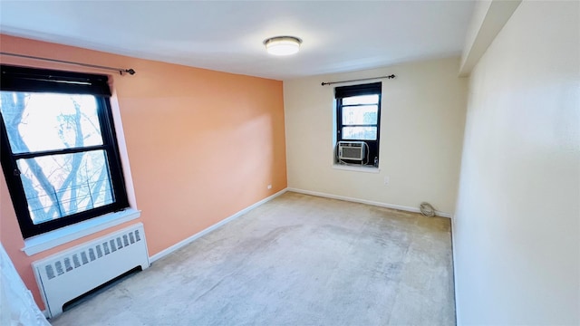 spare room featuring radiator heating unit, light colored carpet, and cooling unit