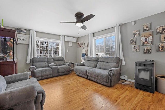 living room featuring hardwood / wood-style flooring, a wall unit AC, a wood stove, and a baseboard heating unit