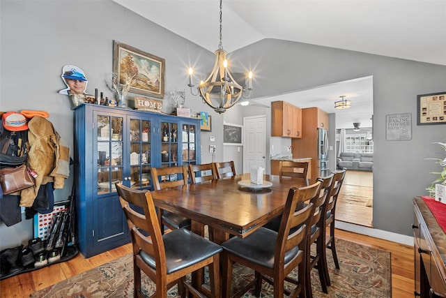 dining space featuring lofted ceiling, light hardwood / wood-style floors, and a notable chandelier