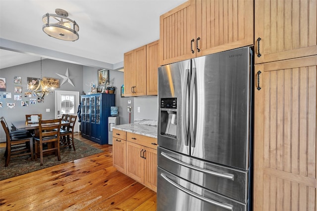 kitchen featuring vaulted ceiling, wood-type flooring, light brown cabinetry, and stainless steel fridge with ice dispenser