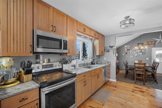 kitchen featuring sink, stainless steel appliances, light stone counters, light hardwood / wood-style floors, and vaulted ceiling